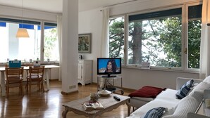 A living room with a television, a dining area with chairs, a coffee table, and a sofa. - Villa Adele (Sori)