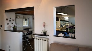 A modern kitchen with a built-in oven, a dining area with a table and chairs, and a living room with a sofa. - ILA1505 House Golia (Genoa)
