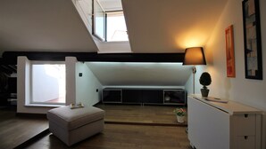 A modern loft bedroom with a skylight, a sofa, a desk, and a potted plant. - ILA1505 House Golia (Genoa)