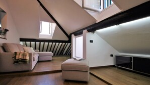 A modern loft bedroom with a sloped ceiling, built-in seating, and a large window providing natural light. - ILA1505 House Golia (Genoa)