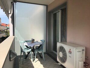 Ein Balkon mit Tisch, Stühlen und einer Mitsubishi-Klimaanlage.