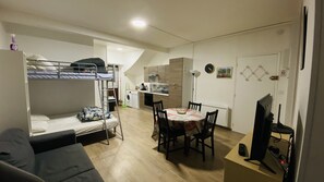 A compact room with bunk beds, a dining table, and a TV.