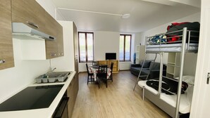 Ein gemütlicher Wohnraum mit Küchenzeile, Essbereich, Etagenbett und Fernseher.