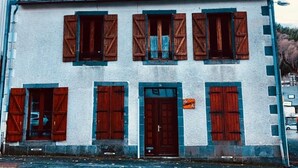 Ein zweigeschossiges Gebäude mit weißer Fassade und dunkelbraunen Fensterläden.