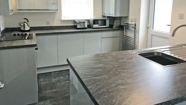 A modern kitchen with grey cabinets, a stainless steel kettle, a toaster, and a microwave. - Great property for exploring the Forest of Dean and surrounding areas. (Mile End, near Coleford)