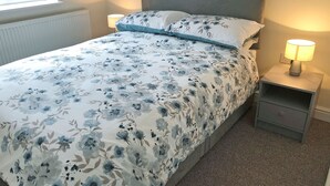 A neatly made bed with a floral bedspread, two bedside lamps, and a small bedside table with a lamp. - Great property for exploring the Forest of Dean and surrounding areas. (Mile End, near Coleford)