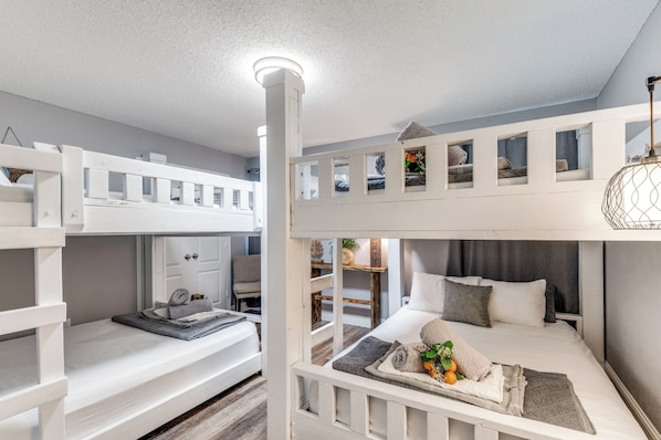A bunk bed room with a white color scheme, a ceiling light, and a small window.