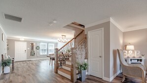 A spacious living area with a wooden staircase, a dining table, and a chair. - Sweet Escape Homes: 3000sf Rustic Modern Home - Center of Dallas & FW (Grand Prairie)