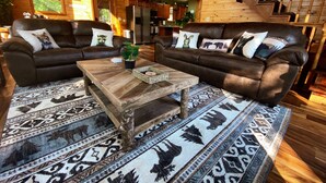 A cozy living room with two brown leather sofas, a wooden coffee table, and patterned rugs. - Stunning Pigeon Forge Pet-Friendly A-Frame Cabin (Sevierville)