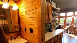 A wooden cabin interior with a wooden sink, cabinets, and a dining area with a rug. - Stunning Pigeon Forge Pet-Friendly A-Frame Cabin (Sevierville)