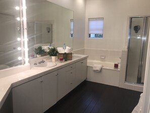 Une salle de bain moderne dotée d’un grand miroir, d’un meuble-lavabo et d’un espace douche.