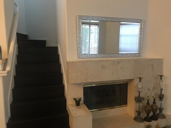 Un escalier menant à un palier agrémenté d’une cheminée et de lampes décoratives.