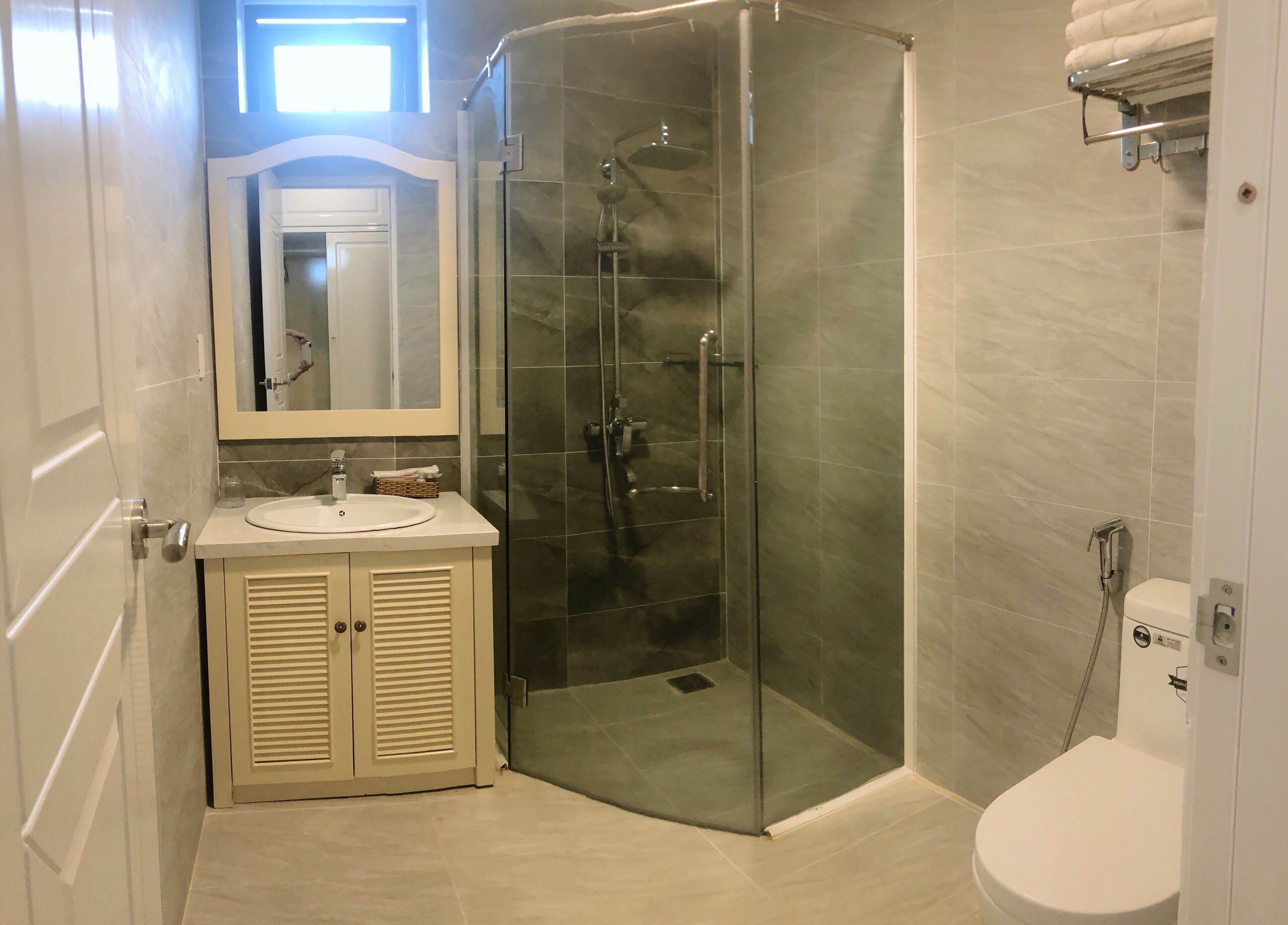 A modern bathroom with a glass-enclosed shower, a sink with a mirror, and a toilet.