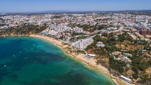 Eine Luftaufnahme einer Küstenstadt mit Strand, Gebäuden und klarem, blauem Wasser.