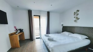 Ein Hotelzimmer mit Bett, Schreibtisch, Fernseher und Blick ins Freie.