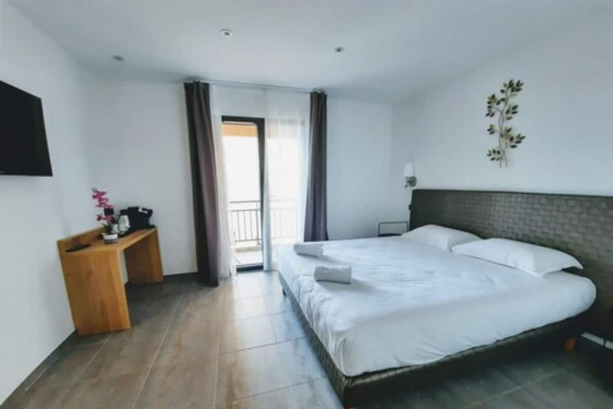 Una habitación de hotel con cama, escritorio, televisor y vistas al exterior.