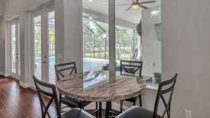 A dining area with a marble table and chairs, large windows, and a ceiling fan. - Everything you need in a home to enjoy Florida. (Lutz)