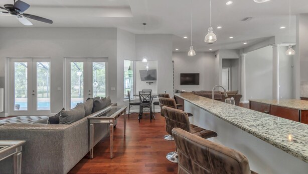 A modern kitchen with a bar area, a dining table, and a seating area with a sofa and chairs. - Everything you need in a home to enjoy Florida. (Lutz)