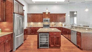 A modern kitchen with wooden cabinets, stainless steel appliances, granite countertops, and pendant lighting. - Everything you need in a home to enjoy Florida. (Lutz)