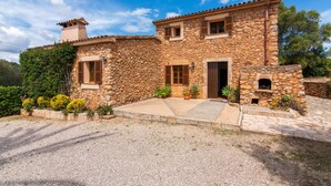 A stone house with a tiled roof, a chimney, a front door, and a small outdoor oven. - Holiday house with private pool, close to Sant Llorenç des Cardassar, Mallorca (Sant Llorenç Des Cardassar)