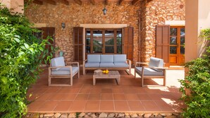 A covered patio with stone walls, wooden furniture, and a view of the surrounding landscape. - Holiday house with private pool, close to Sant Llorenç des Cardassar, Mallorca (Sant Llorenç Des Cardassar)