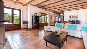 A spacious living area with a high ceiling, a sofa set, a dining table, and a kitchen area visible through a glass door. - Holiday house with private pool, close to Sant Llorenç des Cardassar, Mallorca (Sant Llorenç Des Cardassar)