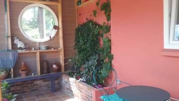 Een terras met een tafel en stoelen, omringd door potplanten en een bakstenen muur.