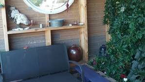 Puinen penkki, pyöreä peili ja viherkasvilla koristeltu seinä.