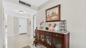 Un pasillo con una consola de madera, un cuadro enmarco y una puerta que da a otra habitación.