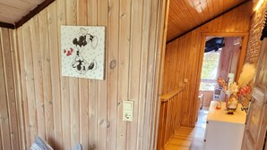 Un interno in legno con un letto, una presa elettrica a muro e un corridoio che porta a una zona cucina.