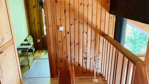 Una scala in legno con corrimano che conduce a un pianerottolo con vista su del verde.
