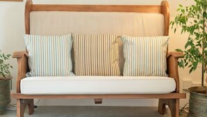 Un banco de madera con asiento y respaldo acolchados, adornado con cojines a rayas.