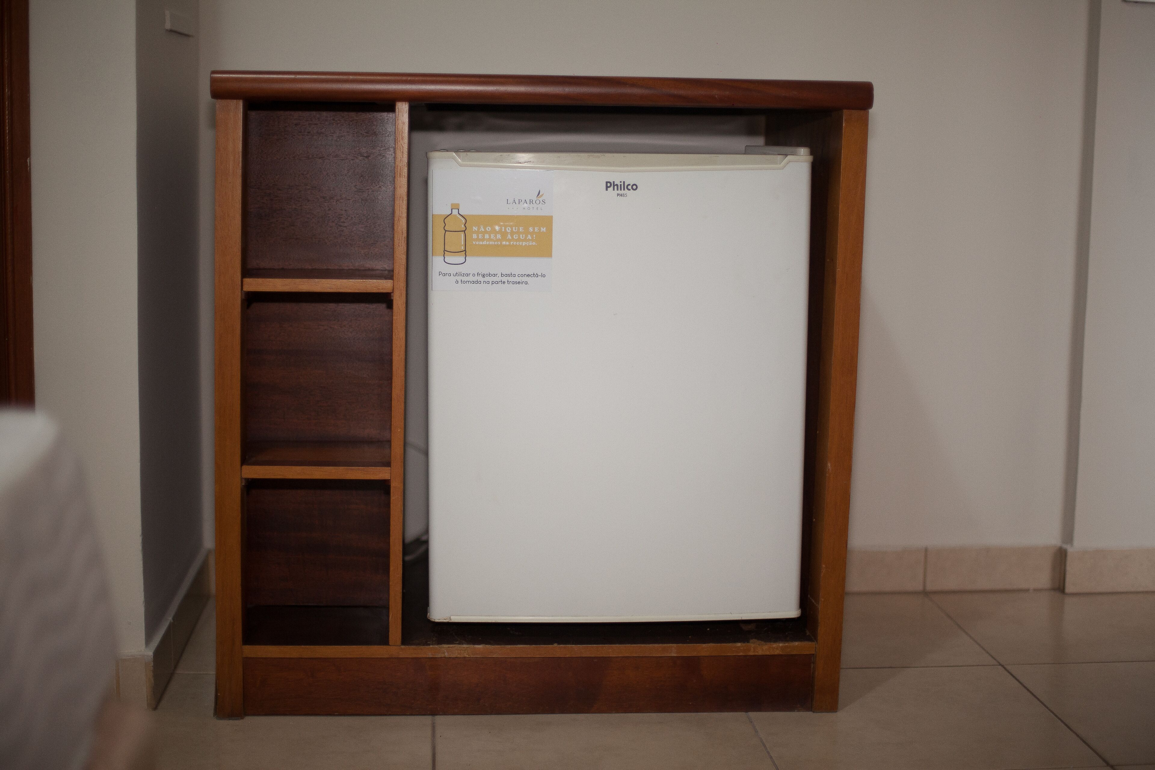 A white refrigerator with a wooden cabinet, a label, and a logo.