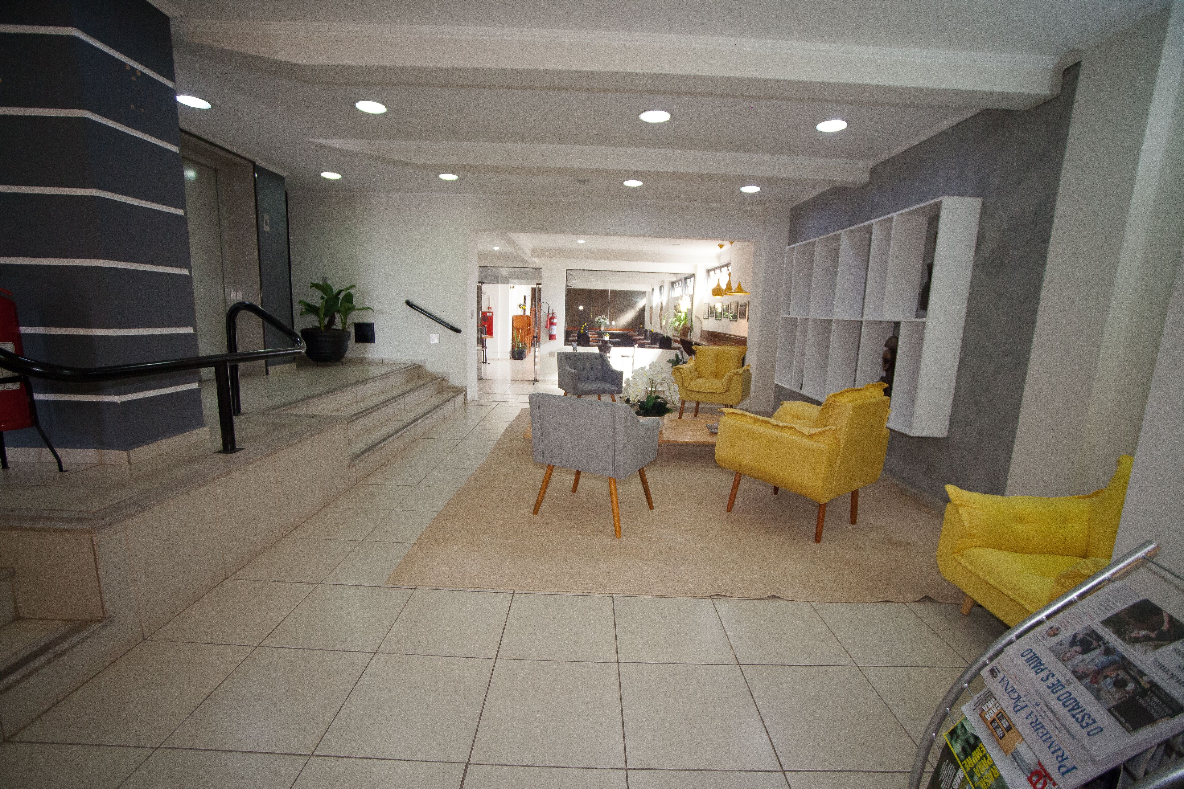 A hotel lobby with a staircase, a reception desk, and seating areas.
