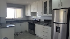 Eine moderne Küche mit weißen Schränken, einem Edelstahl-Kühlschrank, einer Mikrowelle und einem Gasherd.