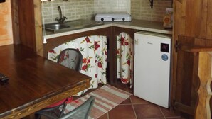 Une cuisine compacte avec des meubles en bois, un réfrigérateur blanc et un coin repas comprenant une chaise et une table.