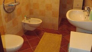 Une salle de bain avec deux toilettes, un bidet, un lavabo et une horloge au mur.
