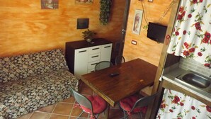 Un espace de vie compact comprenant un canapé, une petite table à manger et un coin cuisine.