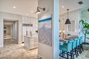 Enjoy meals in the kitchen with a central island and bar stools, featuring a stainless steel range hood and a large window.