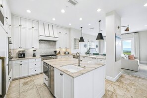 A modern kitchen with white cabinetry, a central island, and a dining area with a view.