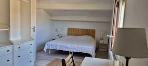 Un dormitorio con una cama, mesitas de noche, un escritorio y una silla.