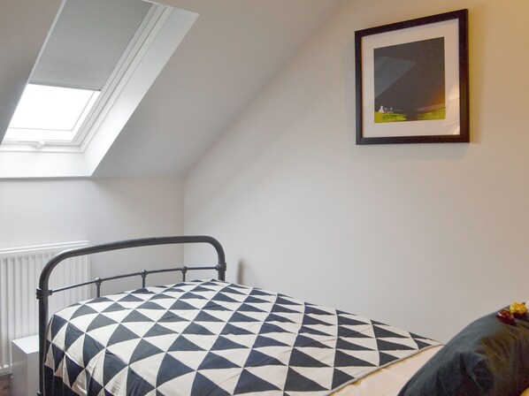 A bedroom with a skylight, a bed with a geometric-patterned bedspread, a framed picture on the wall, and a radiator. - 2 bedroom accommodation in Grosmont, near Abergavenny (Grosmont, near Abergavenny)