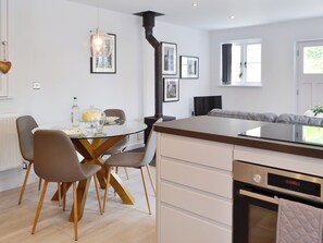 Une cuisine moderne avec une table à manger, des chaises, un four encastré et une grande fenêtre.