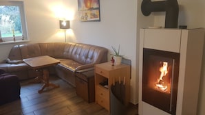 A cozy living room with a leather sofa, a small table, a fireplace, and a painting on the wall. - Blooming vacation home at Scharmützelsee (Wendisch Rietz)
