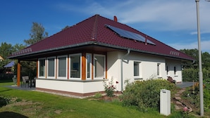 A single-story house with a red-tiled roof, large windows, and a small garden area. - Blooming vacation home at Scharmützelsee (Wendisch Rietz)