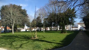 A park with a paved path, trees, and buildings in the background. - Villa hyper center, quiet, 4 bedrooms, 2 bathrooms, enclosed garden (200m2) WIFI (Royan)