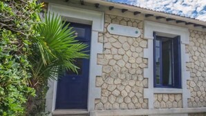 A stone building with a blue door and windows, surrounded by greenery. - Villa hyper center, quiet, 4 bedrooms, 2 bathrooms, enclosed garden (200m2) WIFI (Royan)