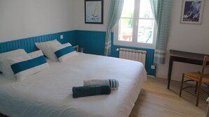 A bedroom with a large bed, a chair, a desk, and a window with curtains. - Villa hyper center, quiet, 4 bedrooms, 2 bathrooms, enclosed garden (200m2) WIFI (Royan)