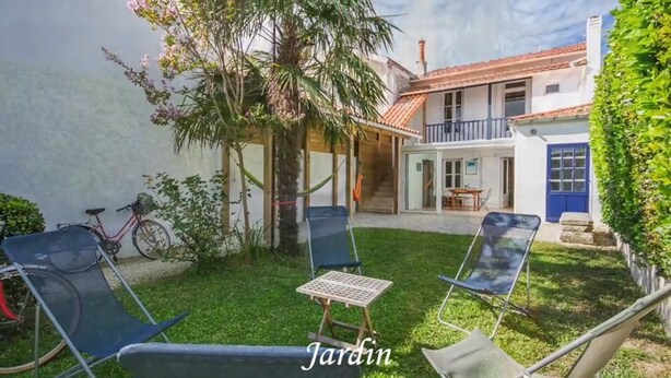 A garden with two lounge chairs, a small table, and a bicycle. - Villa hyper center, quiet, 4 bedrooms, 2 bathrooms, enclosed garden (200m2) WIFI (Royan)