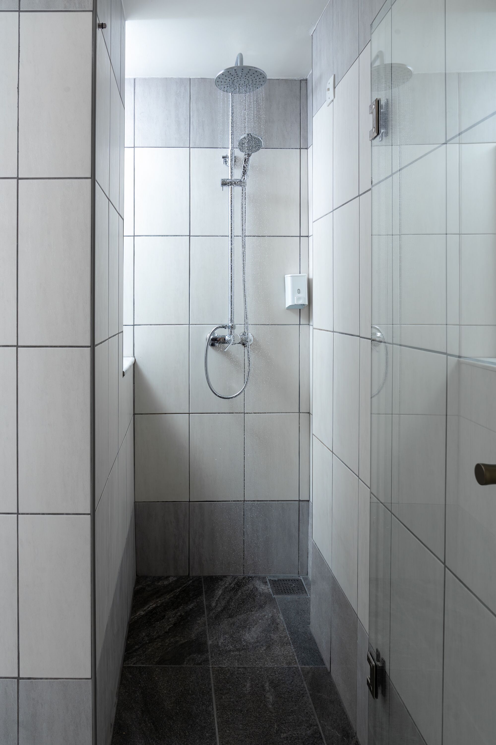 Eine moderne Dusche mit Handbrause und Armaturen an der Wand.